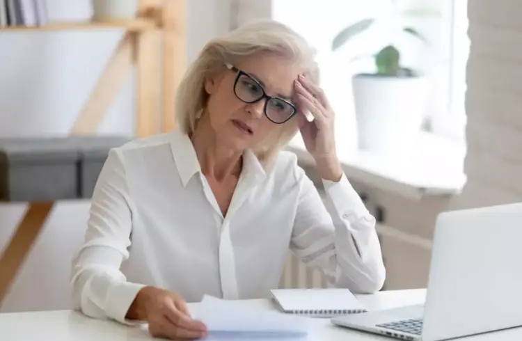Mulher idosa com expressão de preocupação diante de problemas no financiamento Minha Casa Minha Vida após perder o emprego.