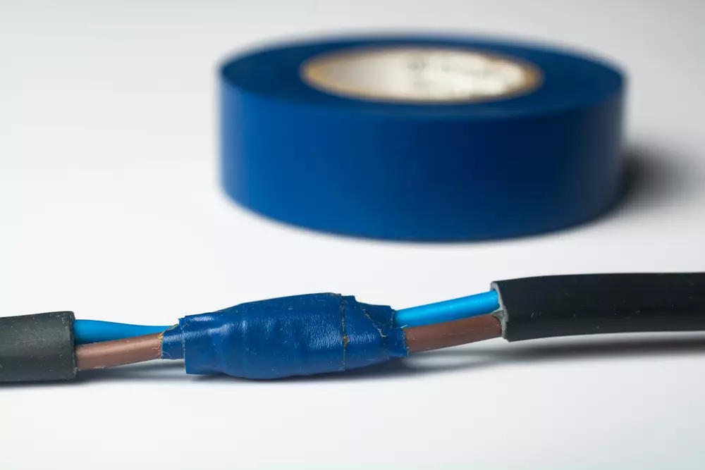 Um fio desencapado e coberto de forma desleixada por uma fita isolante em cor azul. Uma espécie de reparo caseiro. Esse seria um dos hábitos perigosos em casa.