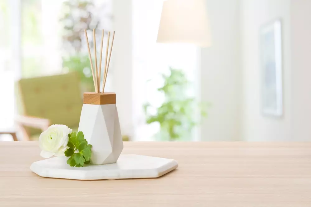 Decoração de ambiente com difusor de aromas, flores e iluminação natural, criando um espaço convidativo e relaxante.