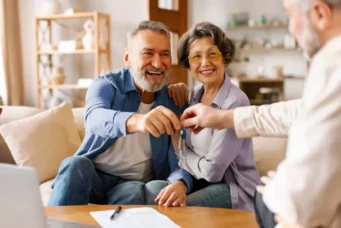 Homem aposentado feliz ao lado de sua esposa recebendo as chaves de um imóvel, simbolizando aprovação de financiamento imobiliário na terceira idade.