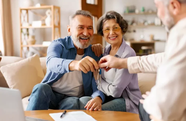 Homem aposentado feliz ao lado de sua esposa recebendo as chaves de um imóvel, simbolizando aprovação de financiamento imobiliário na terceira idade.