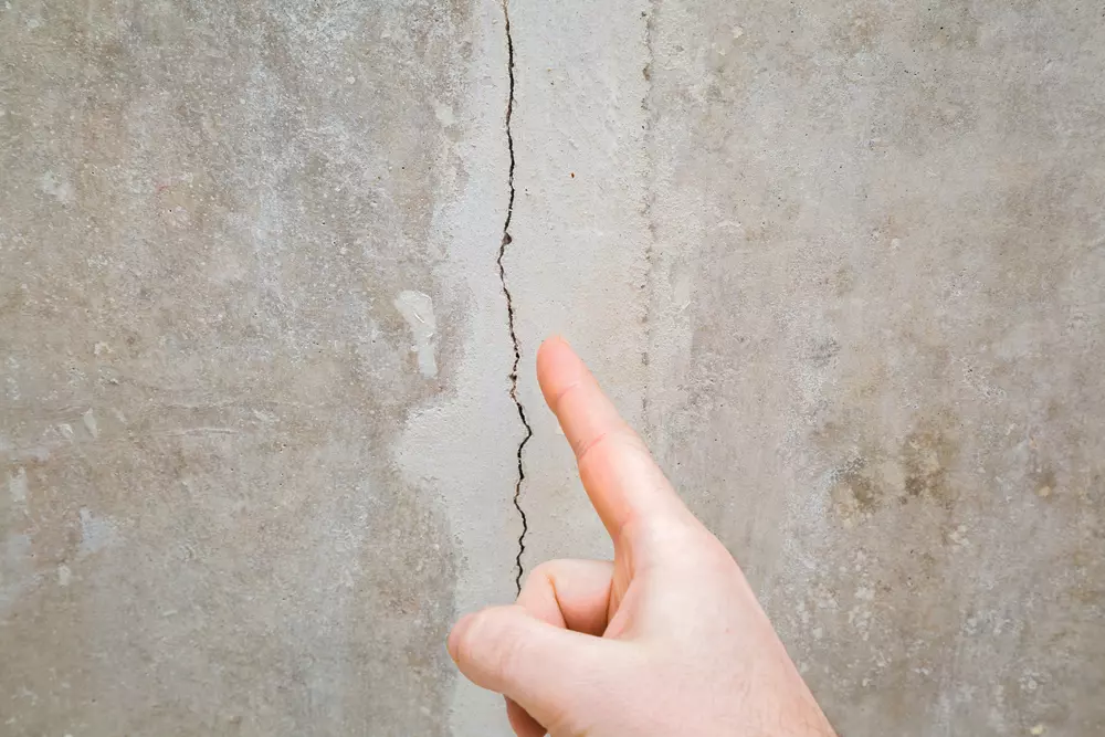 Uma parede de concreto com uma rachadura, destacando a importância da garantia estrutural na manutenção e segurança de edificações.
