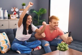 Casal feliz comemorando conquista do primeiro apê, destacando a condição legal para compra do imóvel, na sala moderna com decoração acolhedora.