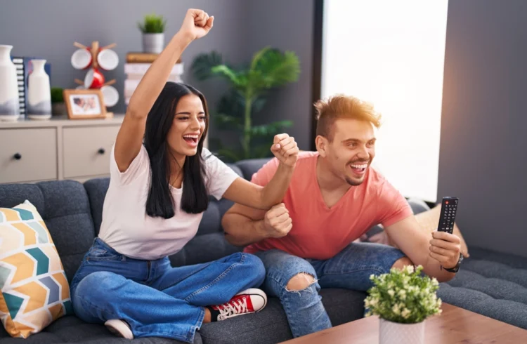 Casal feliz comemorando conquista do primeiro apê, destacando a condição legal para compra do imóvel, na sala moderna com decoração acolhedora.
