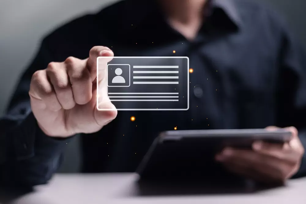 Pessoa segurando um cartão de identificação digital com detalhes de usuário, representando documentação incompleta ou digitalização de documentação.