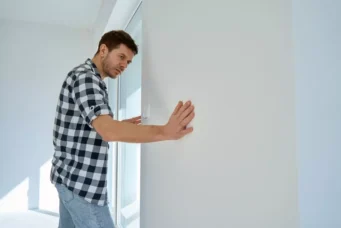 Homem verificando a parede para garantir a integridade estrutural de uma construção, destacando a importância da garantia estrutural em obras.