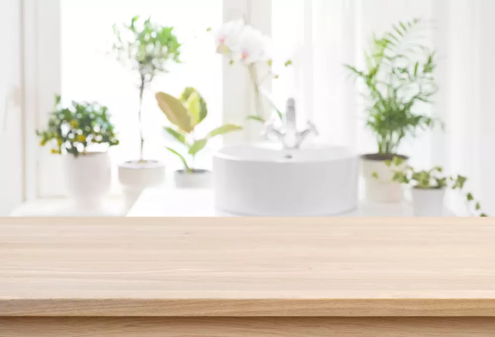 bancada de madeira na cozinha, com várias plantas verdes ao fundo, na iluminação natural, criando ambiente aconchegante e natural.