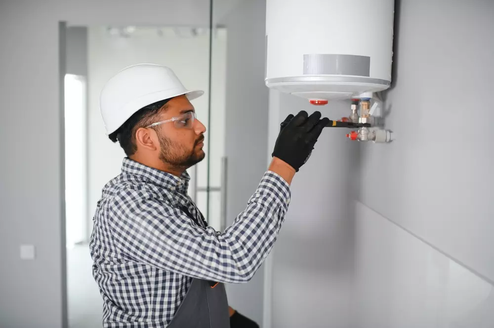Instalador verificando a conexão de um aquecedor de água, garantindo normas e segurança na instalação para evitar acidentes.