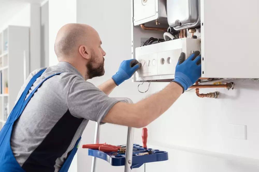 Técnico instalando ou fazendo manutenção em aquecedor de água, importante entender antes de adquirir esse equipamento.