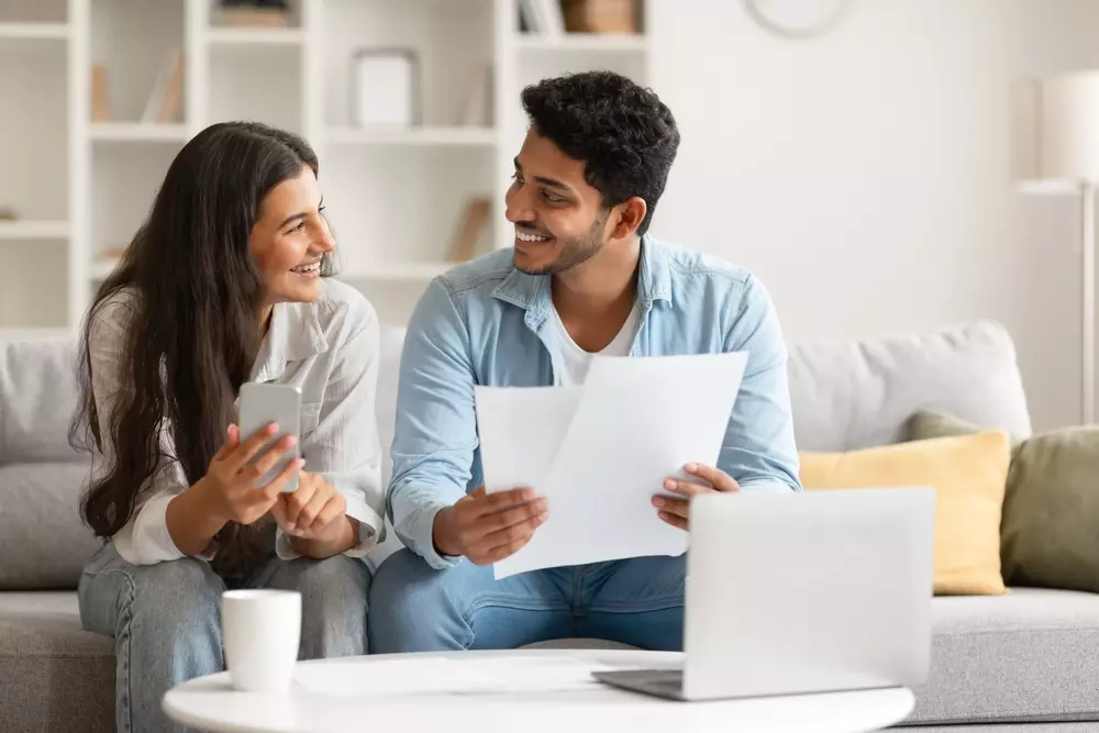 Casal feliz discutindo documentos em casa, promovendo organização e gestão eficiente de documentação.