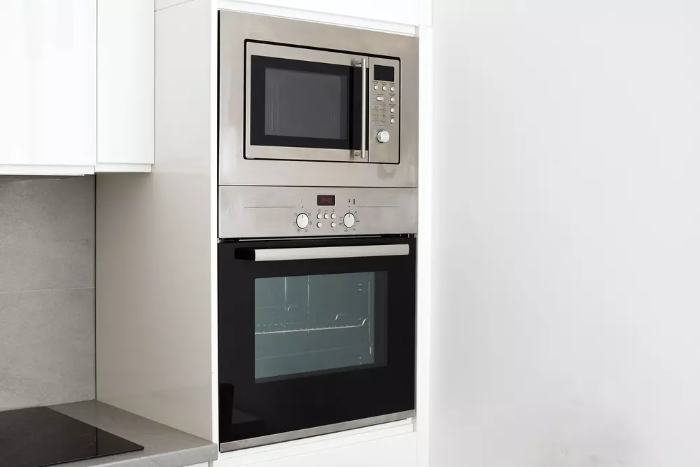 Configuração de eletrodomésticos embutidos na cozinha com forno e micro-ondas integrados em armário planejado.
