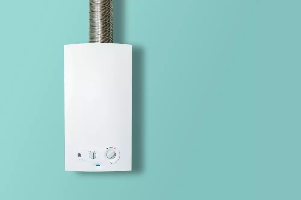 Aquecedor de água a gás branco instalado em uma parede azul, representando uma opção de aquecedores de água eficientes para residências.
