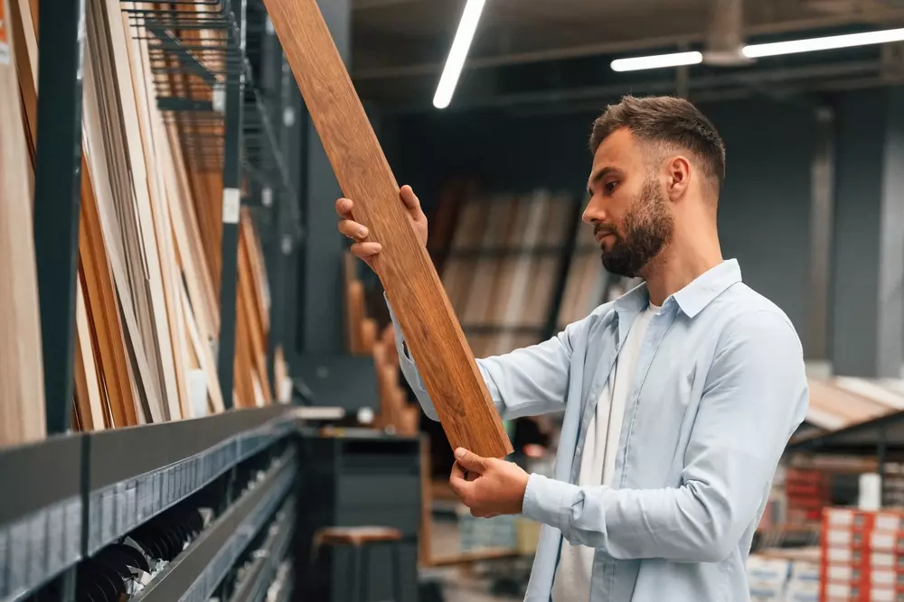 Homem escolhe diferentes tipos de madeira ideais para bancadas de cozinha em loja de materiais de construção.
