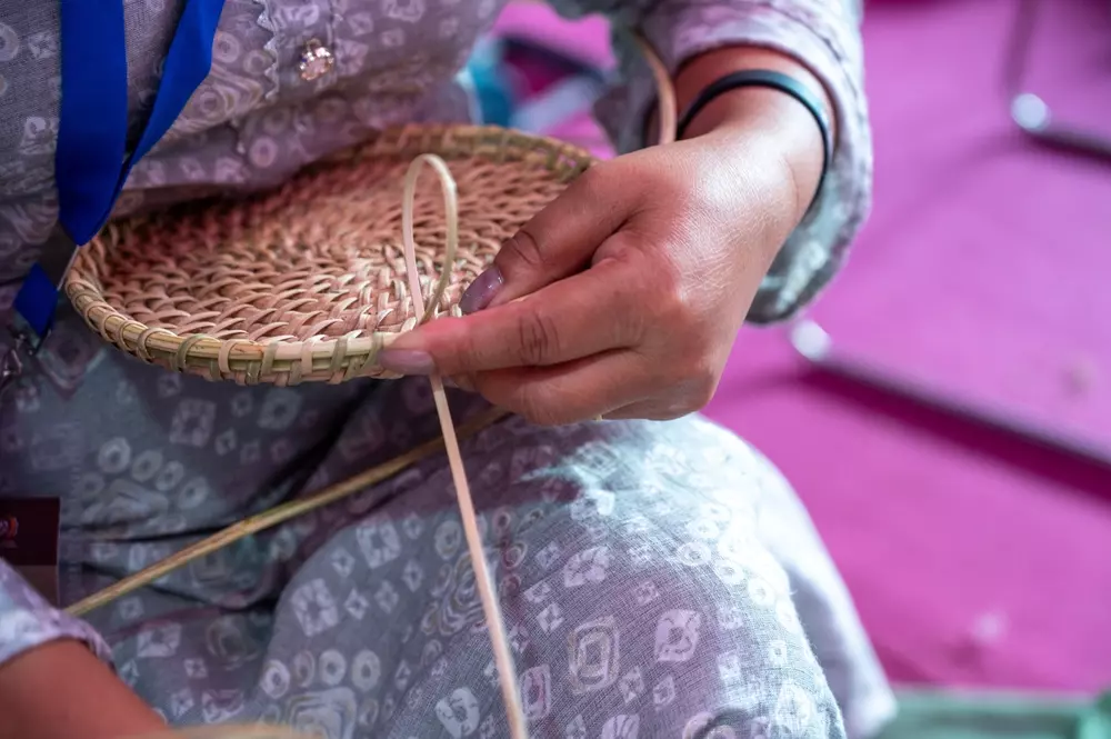 Pessoa entrelaçando palhinha indiana artesanal, símbolo da rica história da cultura e artesanato antigos.