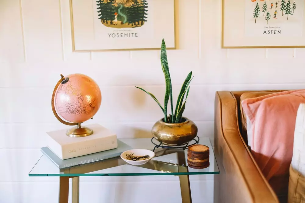 Decoração de estilo cluttercore com objetos variados, incluindo planta, globo, livros e quadros decorativos na parede, criando um espaço aconchegante e cheio de personalidade.