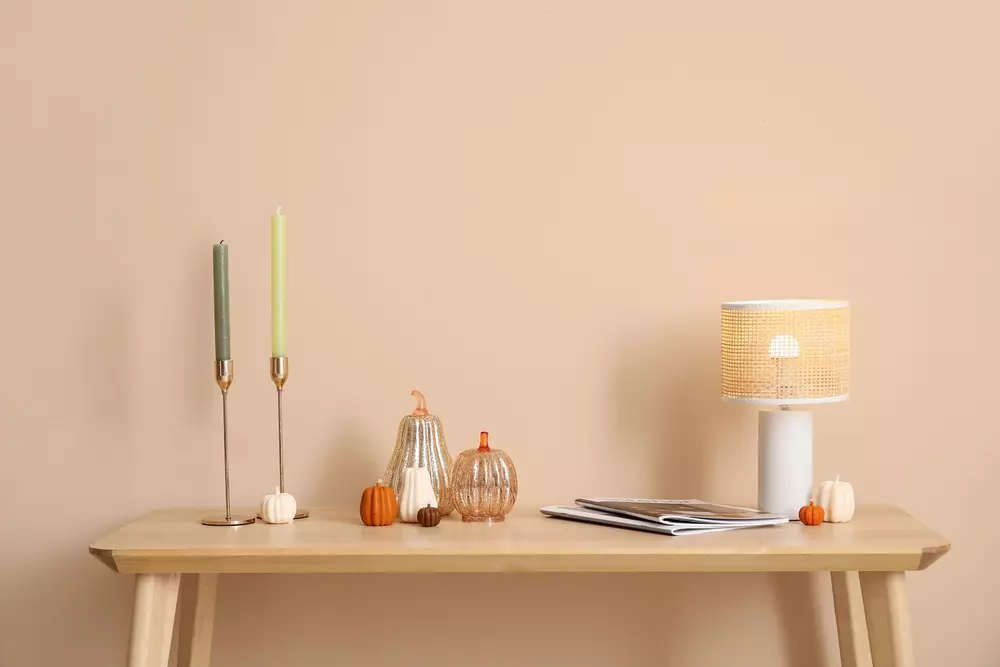 Abajur de tamanho médio em uma composição decorativa com velas e pequenos objetos, ideal para complementar ambientes com o tamanho do abajur adequado.