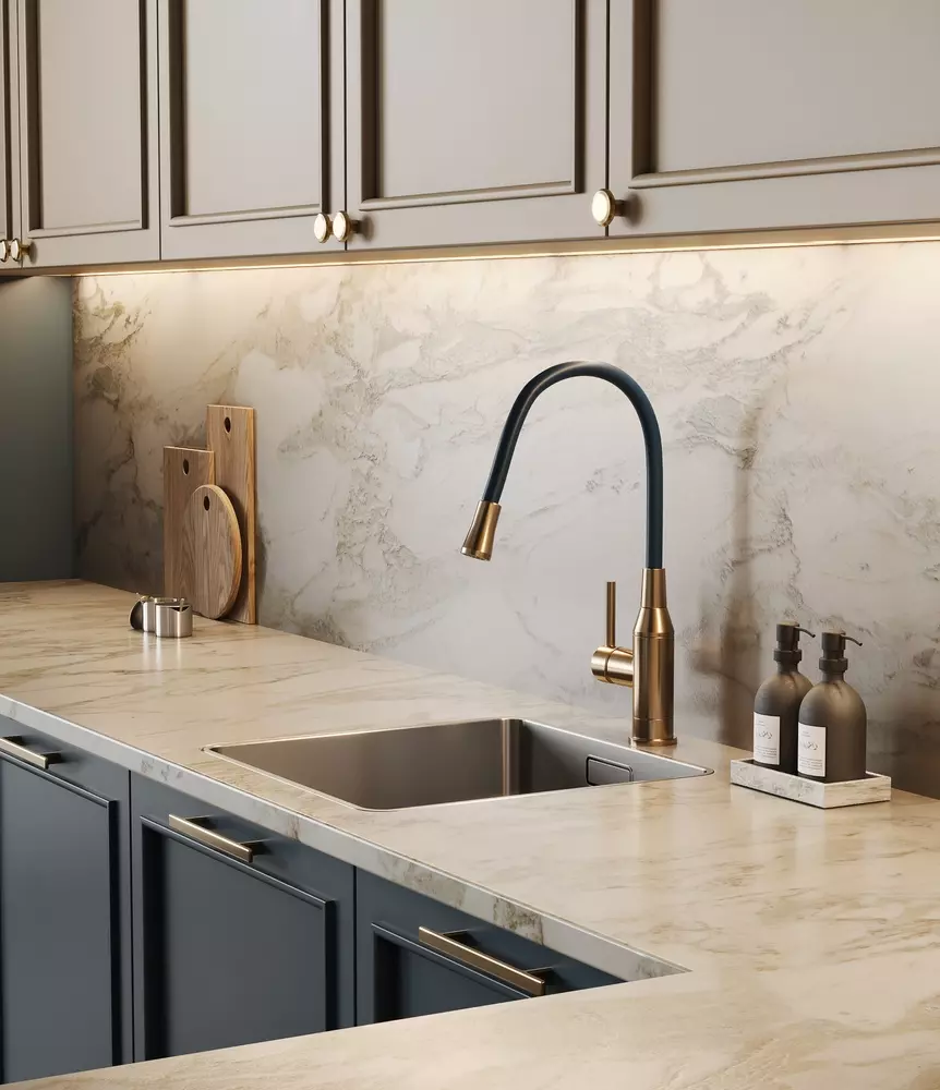 Cozinha com decoração clássica, armários cinza claro, pia de aço inox, backsplash de mármore, torneira dourada e detalhes elegantes, ideal para ambientes sofisticados.
