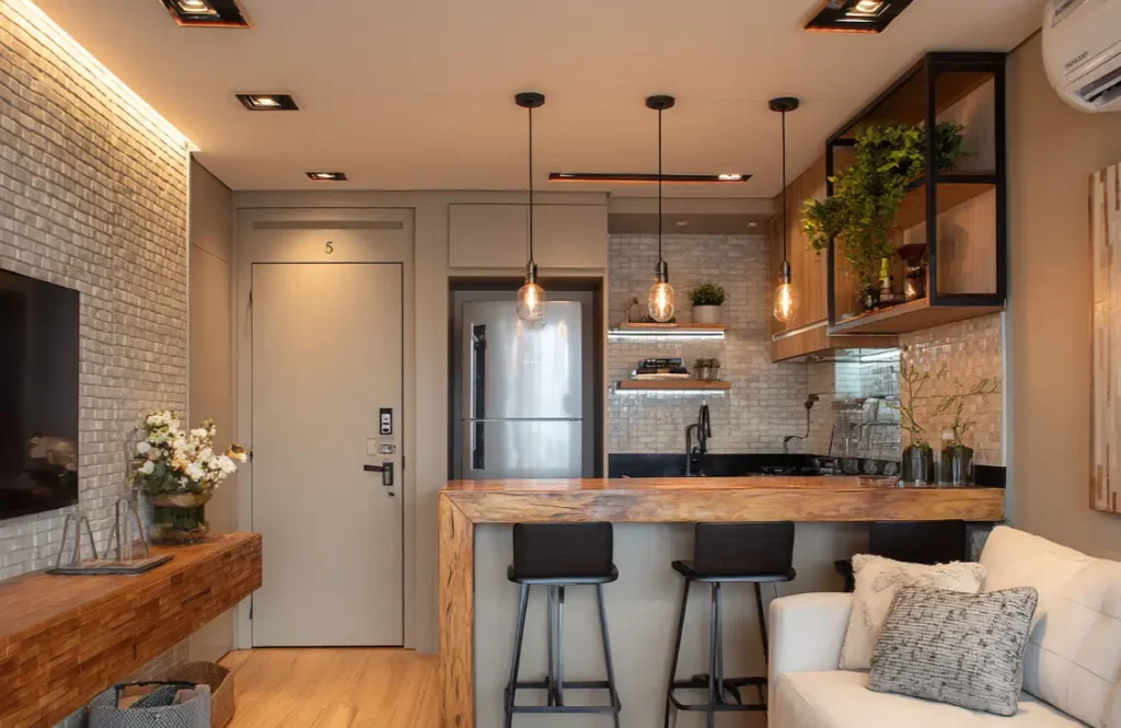 ma cozinha moderna com iluminação de pendentes, parede de tijolos aparentes, móveis planejados e uma ilha central