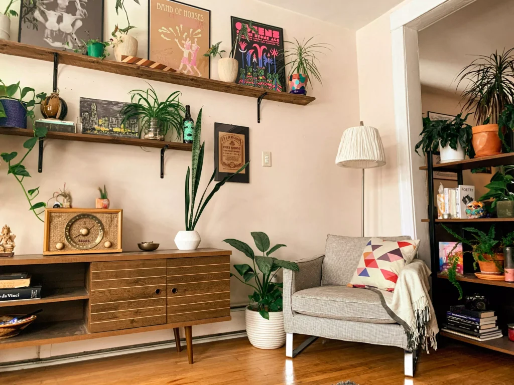 Decoração afetiva com estilo cluttercore, apresentando prateleiras com objetos coloridos, plantas variadas e uma sala aconchegante com móveis vintage e detalhes despojados.