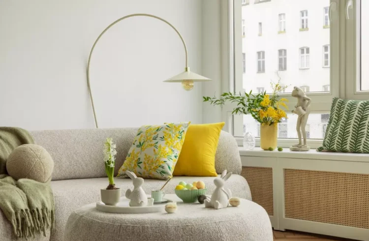 Decoração de primavera na sala com almofadas coloridas, vasinhos com flores, coelhos de cerâmica e elementos decorativos que transmitem a beleza da estação.