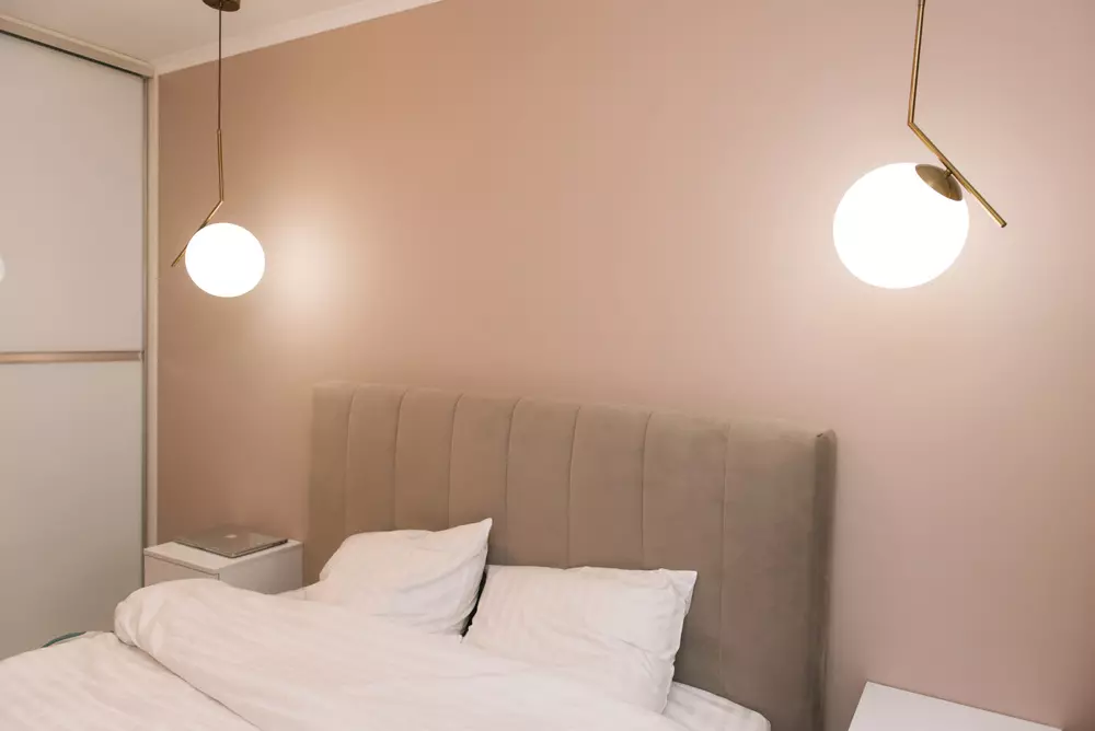 Luz alta na cabeceira da cama em um quarto com luminárias modernas e detalhes de decoração minimalista.