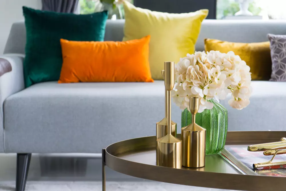 Decoração moderna com almofadas coloridas em um sofá cinza, detalhes de decoração com estampas variadas e cores vibrantes, ideal para quem gosta de cluttercore.