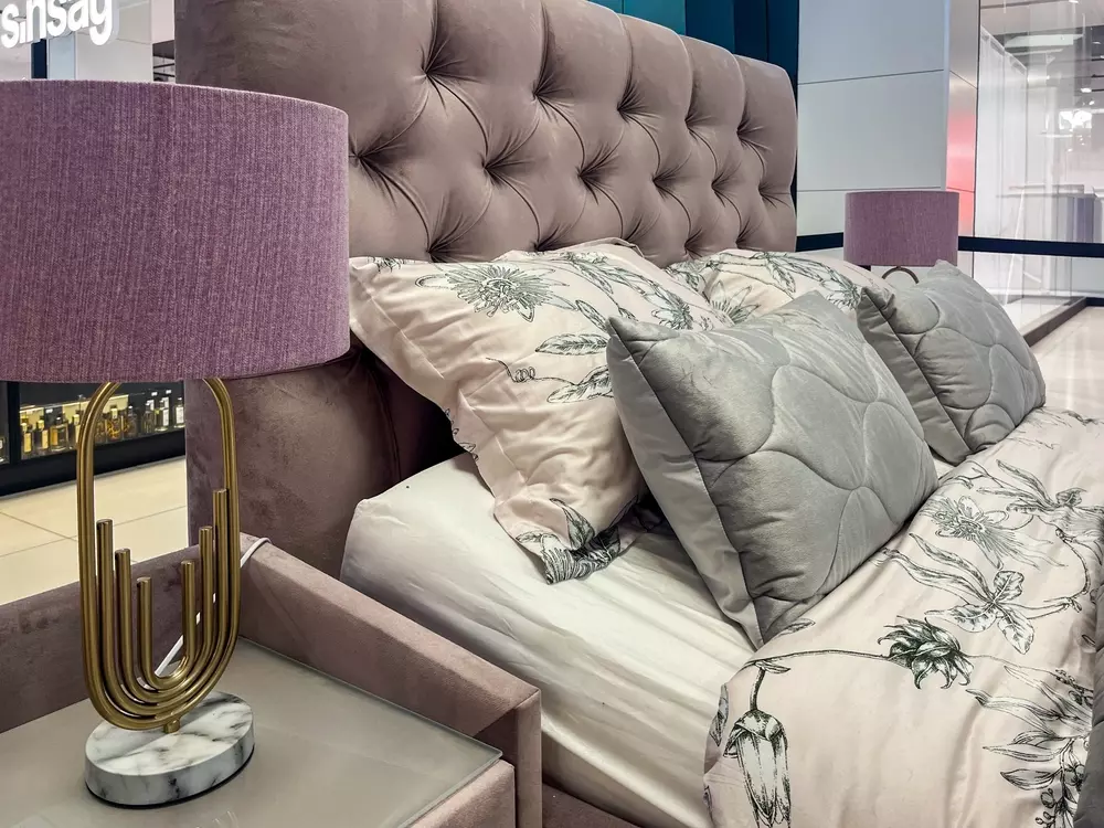 Cama com cabeceira estofada em estilo romântico, almofadas decorativas elegantes, luminária de mesa rosa e móveis com personalidade, decoração de quarto sofisticado.
