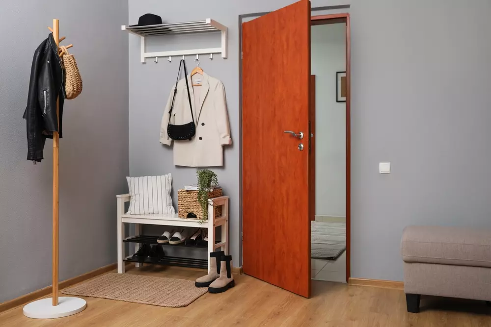 entrada com espaço organizado, cabideiro com roupas, sapatos e uma porta de madeira