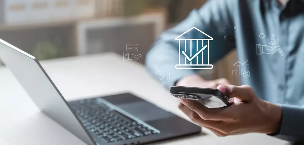 Pessoa utilizando telefone celular com ícone de economia e finanças, destacando o conceito de pagar-se primeiro para uma gestão financeira saudável.