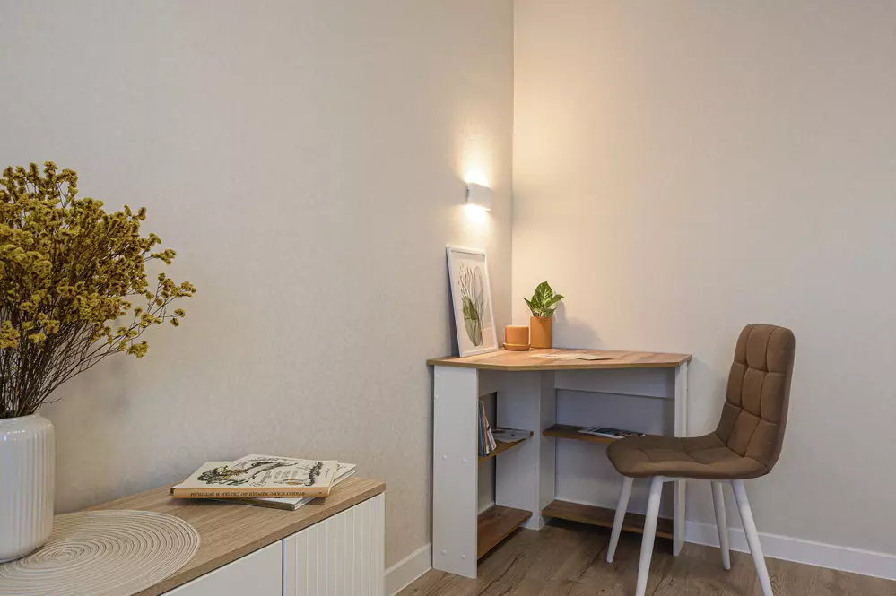 Um espaço de escritório ou home office organizado com uma mesa simples, uma cadeira confortável e decoração minimalista com plantas e quadros