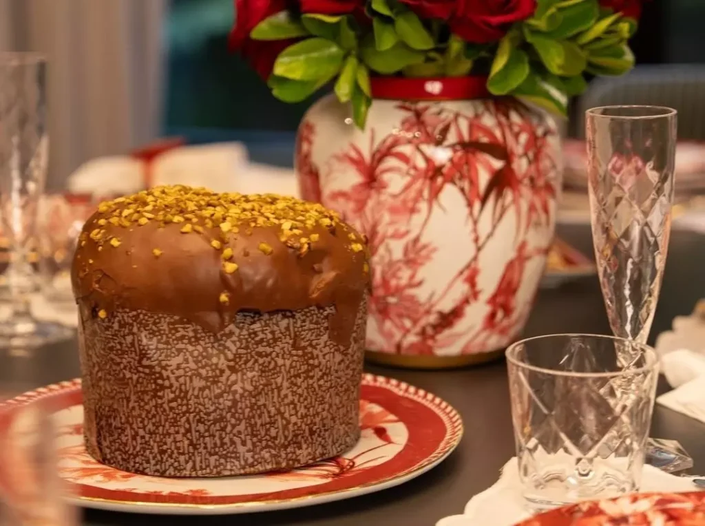 Panetone de chocolate decorado e vaso de flores vermelhas