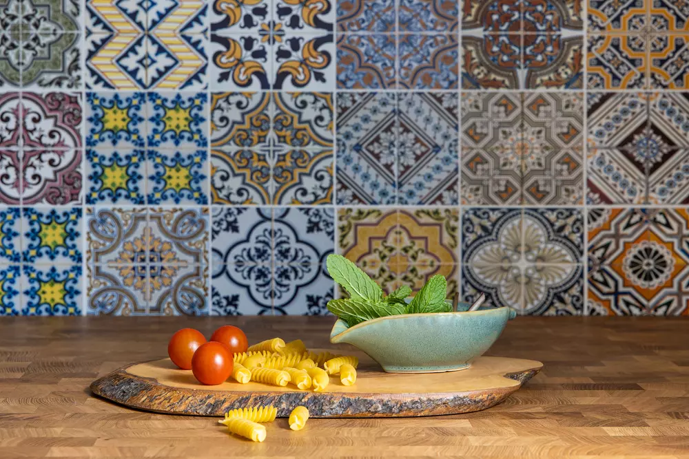 Azulejos portugueses coloridos e ladrilhos hidráulicos decoram a parede de uma cozinha, criando um ambiente tradicional e artístico.