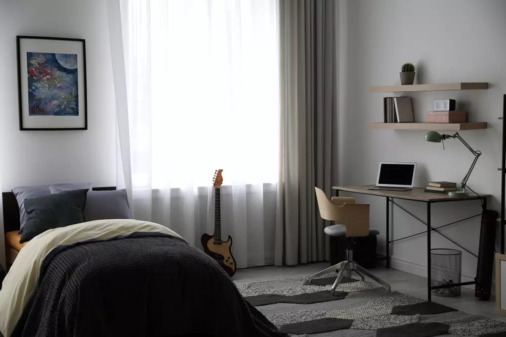 Quarto moderno com decoração minimalista, cama confortável, poltrona de estudo e espaço para criação, ideal para a geração do quarto.