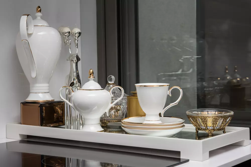 Jogo de louças sofisticado com pratos, xícara, taças e bowl decorativos em ouro e branco, ideal para ocasiões especiais ou decoração de mesa elegante.