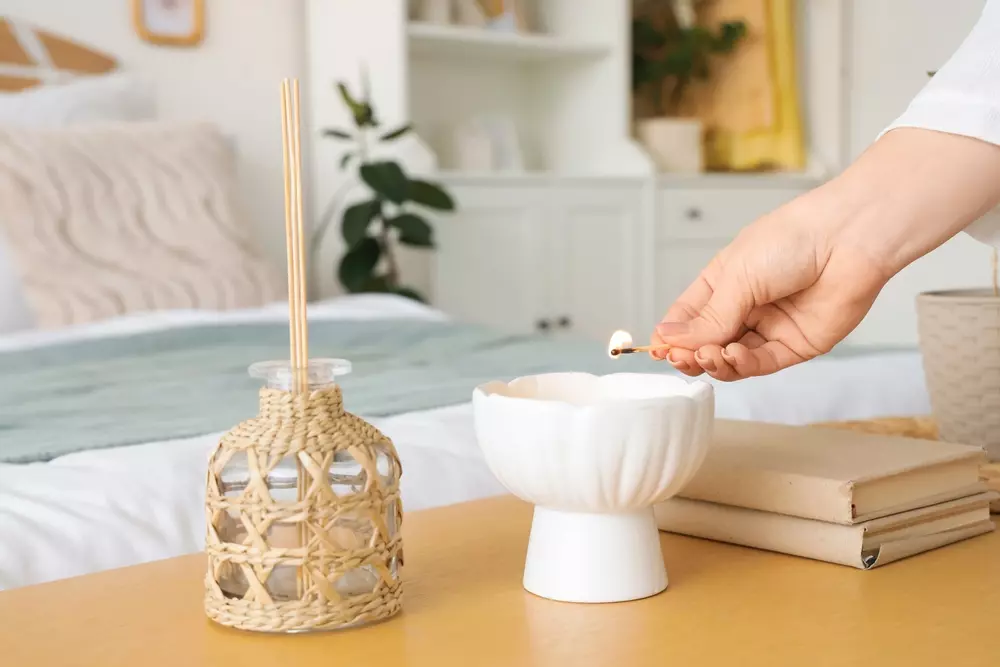 Detalhes sensoriais de uma vela de incenso sendo acesa em um ambiente aconchegante, com foco na mão e na chama do incenso, criando uma atmosfera relaxante com pausas visuais e sensoriais.