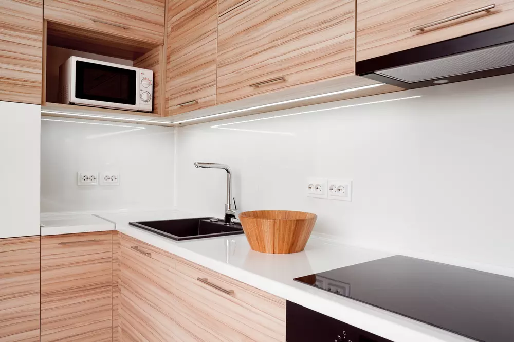 Cozinha moderna com materiais naturais e texturas orgânicas, destaque para bancada de madeira clara, bowl de madeira e detalhes que criam uma decoração biofílica acolhedora.