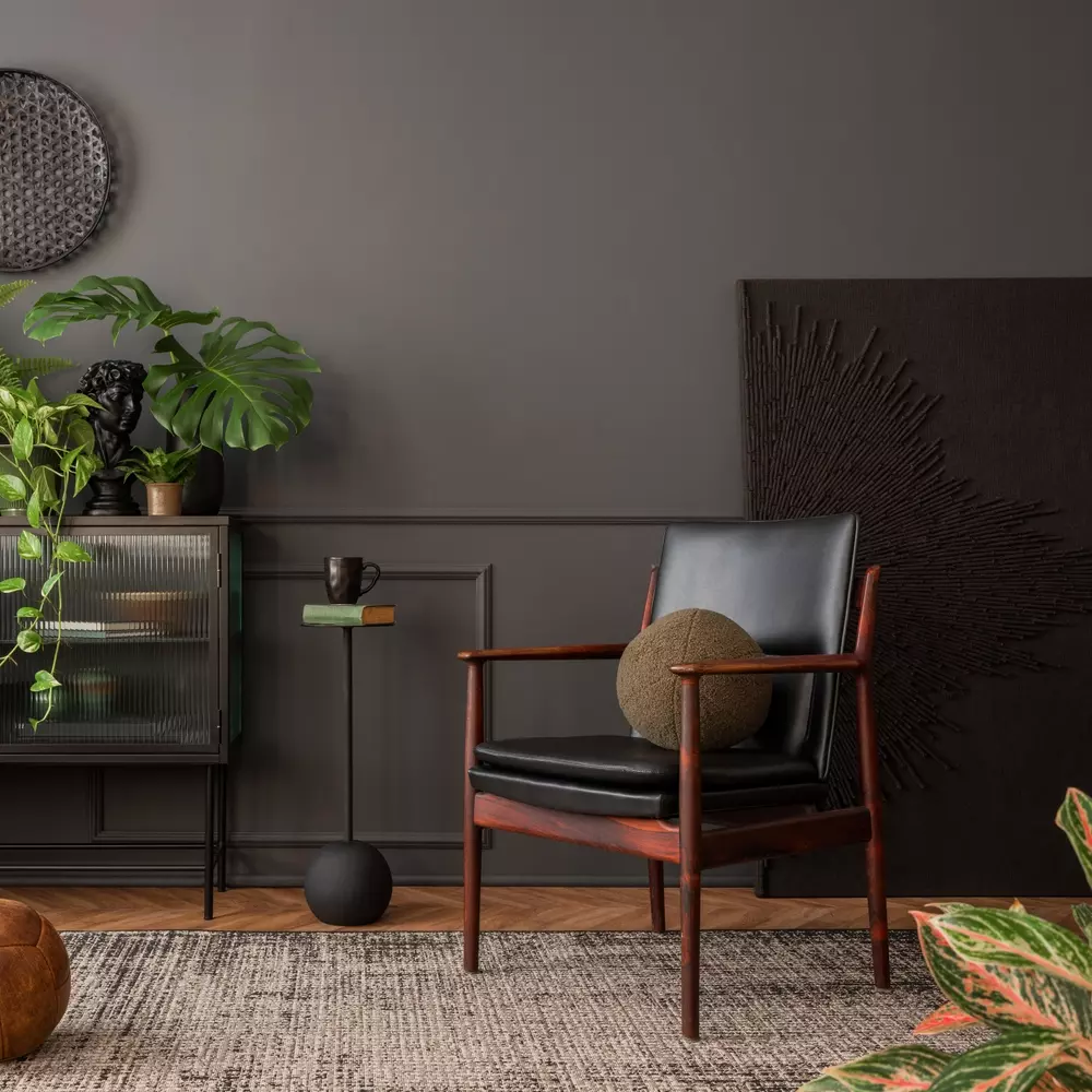 Decoração estilo moto boho com paleta de cores sombria e terrosa, incluindo móveis de madeira escura, plantas verdes, e detalhes decorativos rústicos