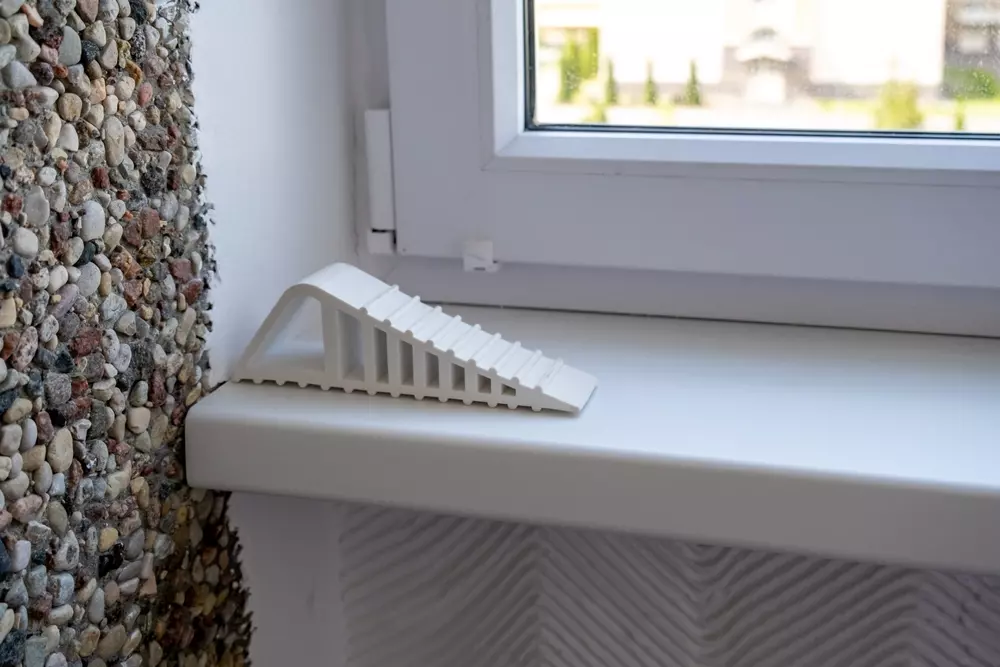 Calços de plástico colocados na janela de uma casa para garantir a vedação adequada e evitar perdas de calor, promovendo eficiência energética.