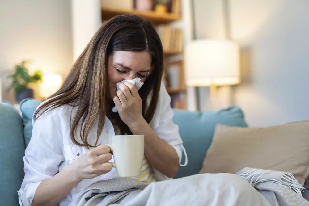 Mulher com sintomas de alergia por mofo em casa, símbolo dos riscos do mofo para a saúde e para a casa.