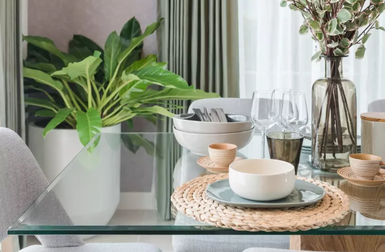 Mesa de jantar moderna com tampo de vidro, decoração com plantas e utensílios de louça