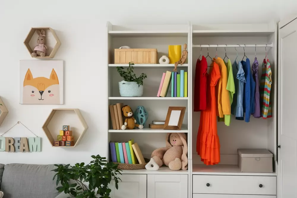 Guarda-roupa infantil organizado com roupas coloridas, livros, brinquedos e decoração de quarto de criança.