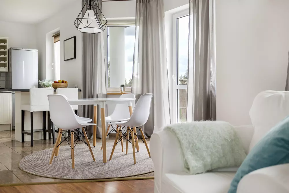 Sala de jantar e cozinha com janelas amplas, cortinas brancas e circulação de ar natural, ideal para ventilação eficiente.