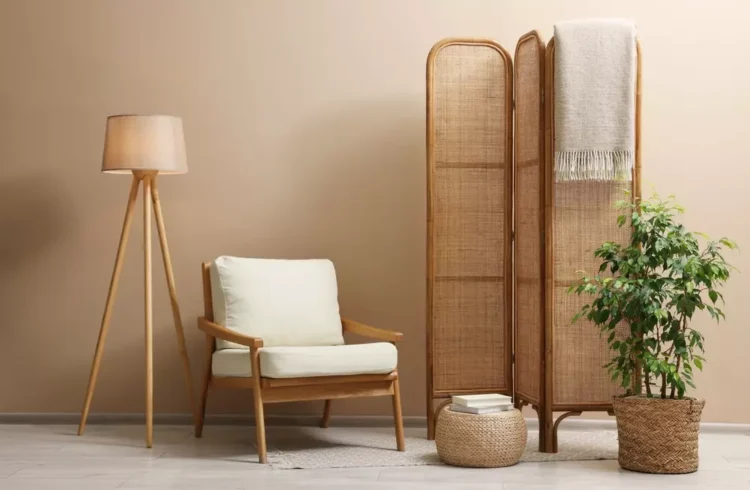Ambiente decorativo com biombo decorativo de fibra natural, uma cadeira confortável de madeira, luminária de pé e plantas para um espaço aconchegante e elegante.