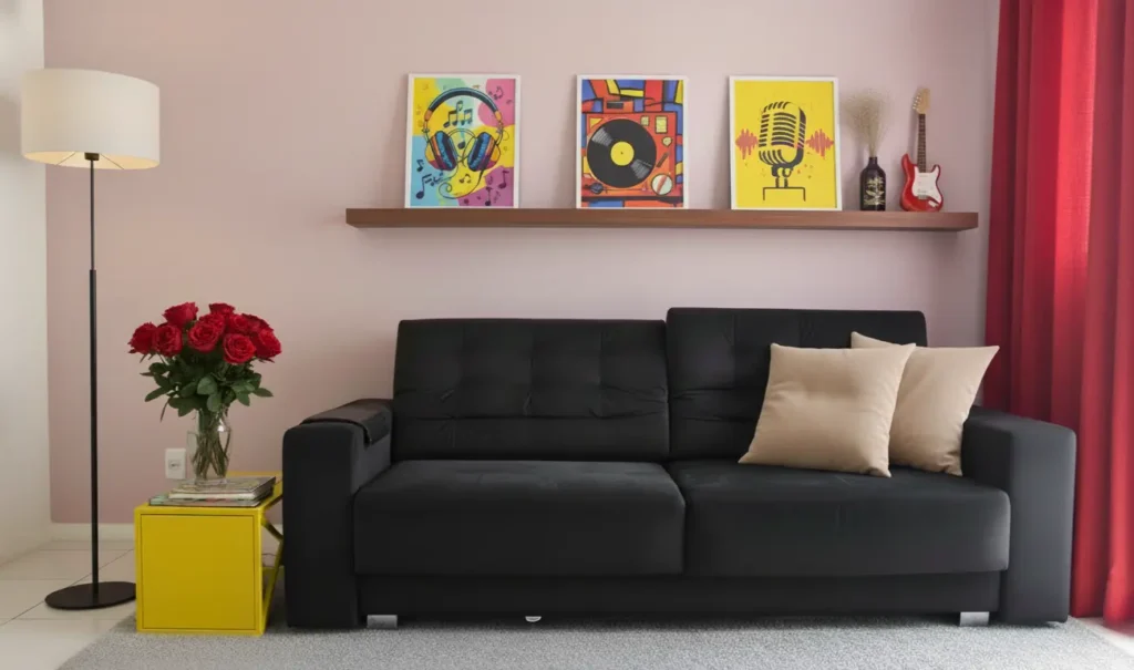Sala decorada com pôsteres de música e tecnologia em fundo de parede rosa, sofá preto com almofadas bege, luminária de pé, mesa amarela com flores vermelhas, e cortinas vermelhas ao lado.