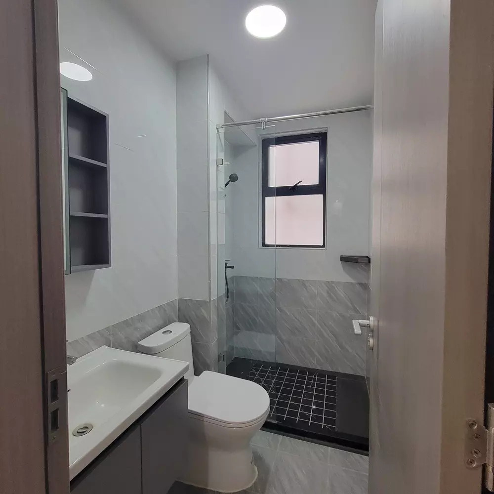 Banheiro pequeno bem organizado com prateleira de vidro, pia moderna e ducha eficiente para otimizar espaços