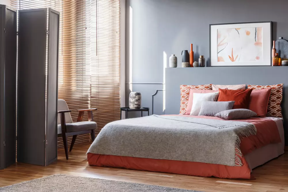 Quarto moderno decorado com almofadas e quadros na parede, com cortinas de madeira, ideal para decoração de ambientes aconchegantes e elegantes.