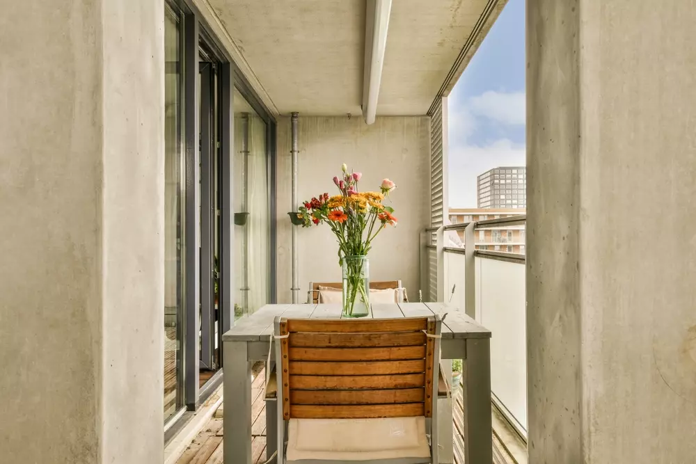 sala integrada com varanda decorada com mesa, cadeiras de madeira e vaso de flores