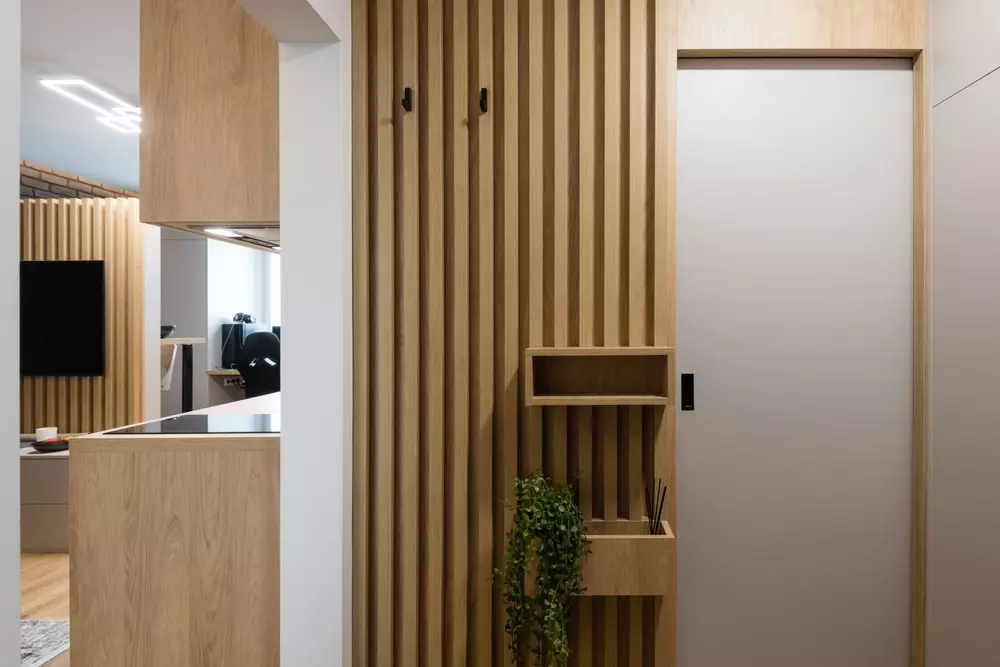 meia parede de lambri com prateleira e planta, ao lado de uma porta clara