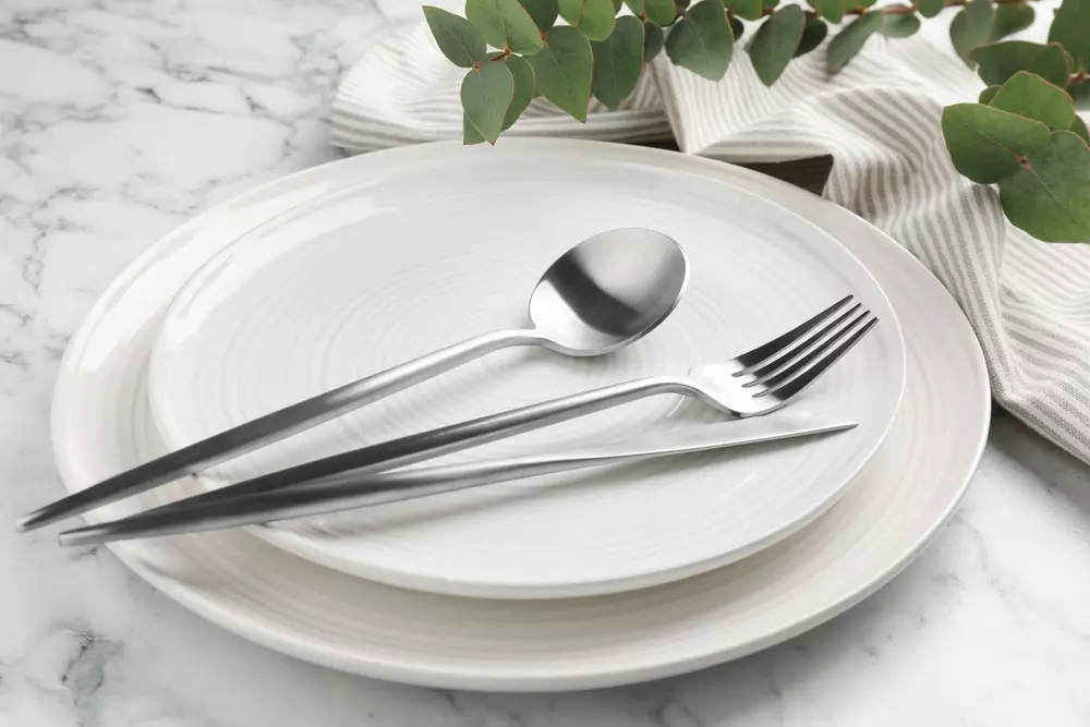 Louças minimalistas brancas e simples decoradas para o Natal, com talheres de aço inox e temática de minimalismo natalino, ideal para decoração clean.