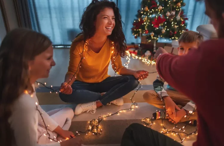 Família celebrando Natal com decoração moderna e iluminação aconchegante, tendência de decoração de Natal 2025 com árvore decorada ao fundo.